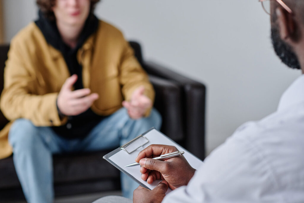 a teen talks to a therapist while sitting in a chair about teen partial hospitalization program