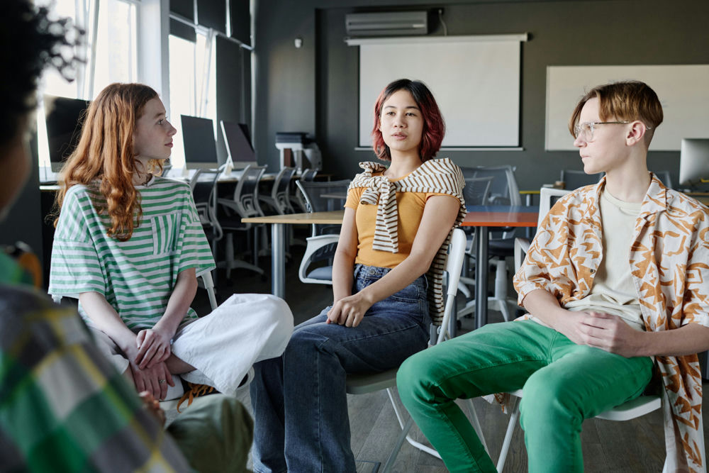 Teens participating in dual diagnosis group therapy led by a clinician at a mental health treatment center.
