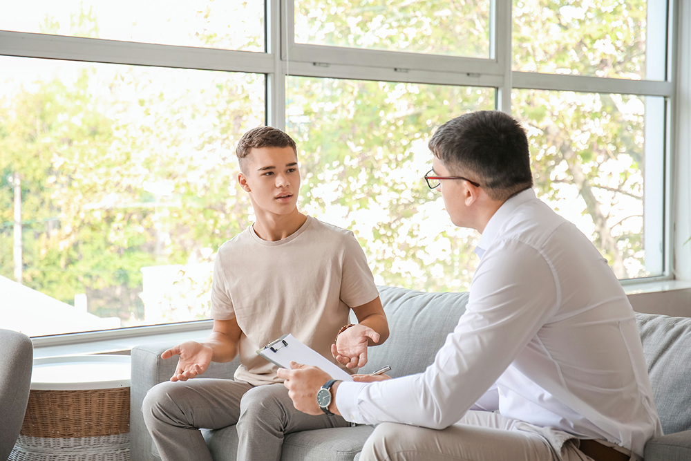 Teen and therapist discussing thought patterns during CBT session – cognitive behavioral therapy for teens.